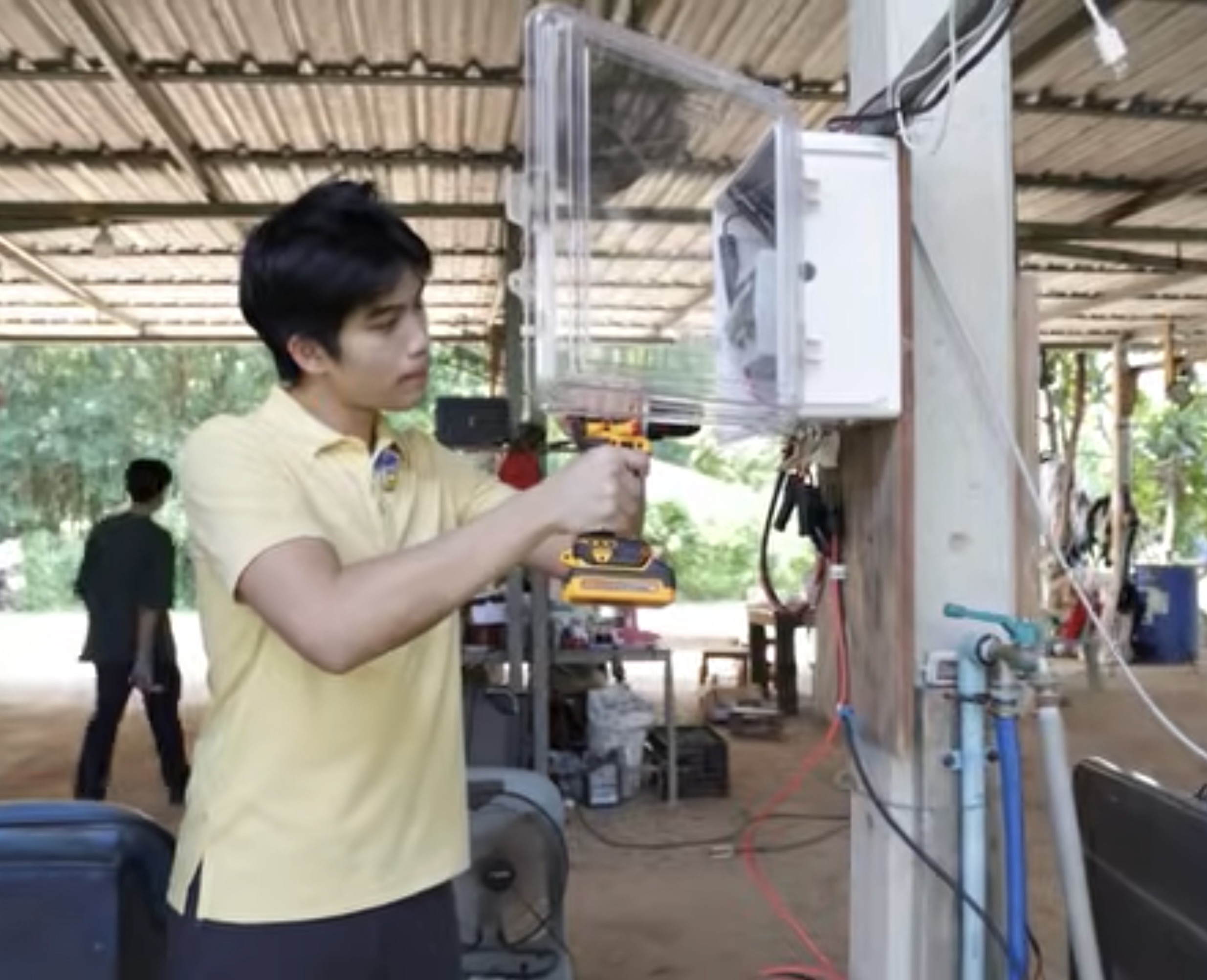 Tul in a yellow shirt using a drill