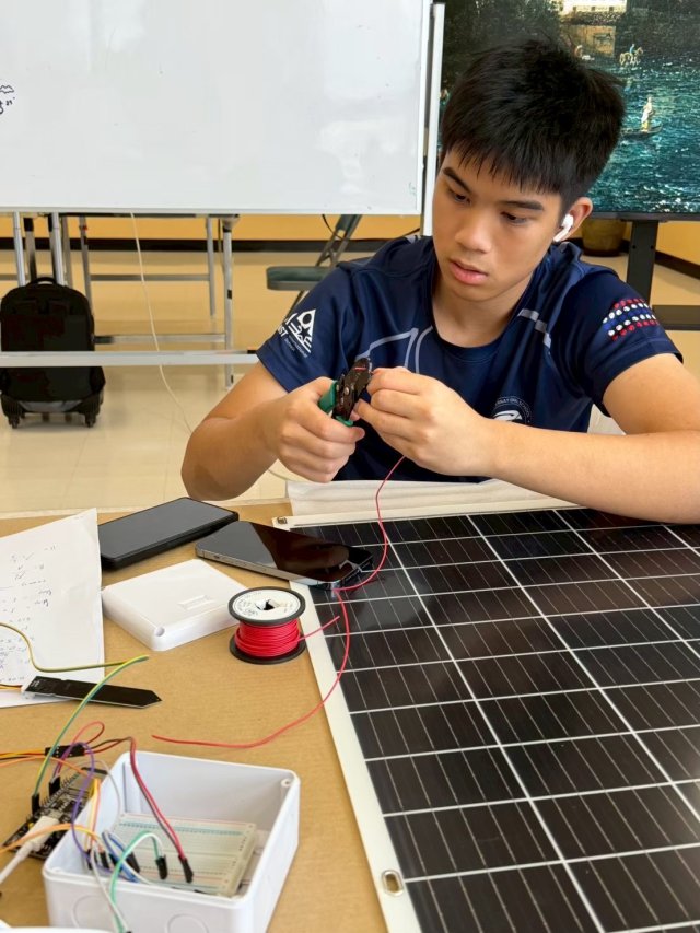 Tul working on the wiring beside a solar panel